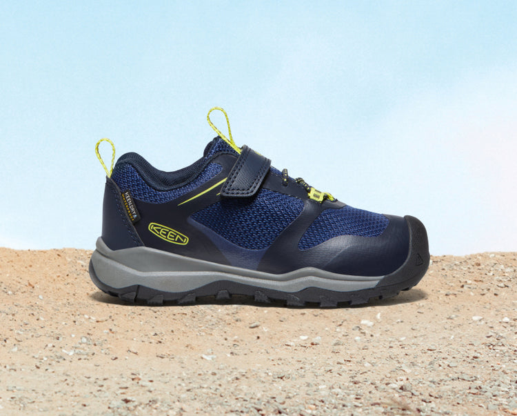 Product shot of little kids dark blue Wanduro waterproof shoe on sand. 
