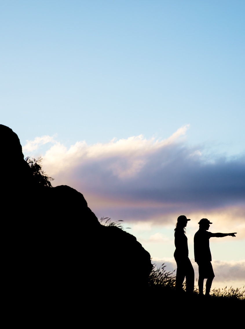 The silhouette of two people standing outside at sunrise.