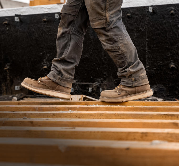 A person wearing a pair of brown Liberty work boots on a job site.