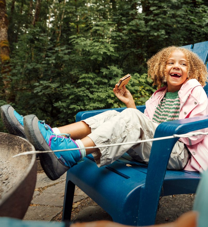 Young girl wearing blue Howser Chukka boots and sitting in an adirondack chair with her feet up. 