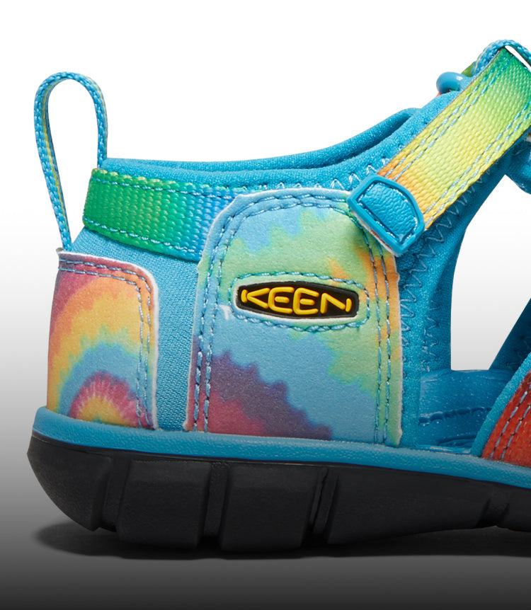 A close-up of a blue and tie-dye Seacamp kids' sandal.