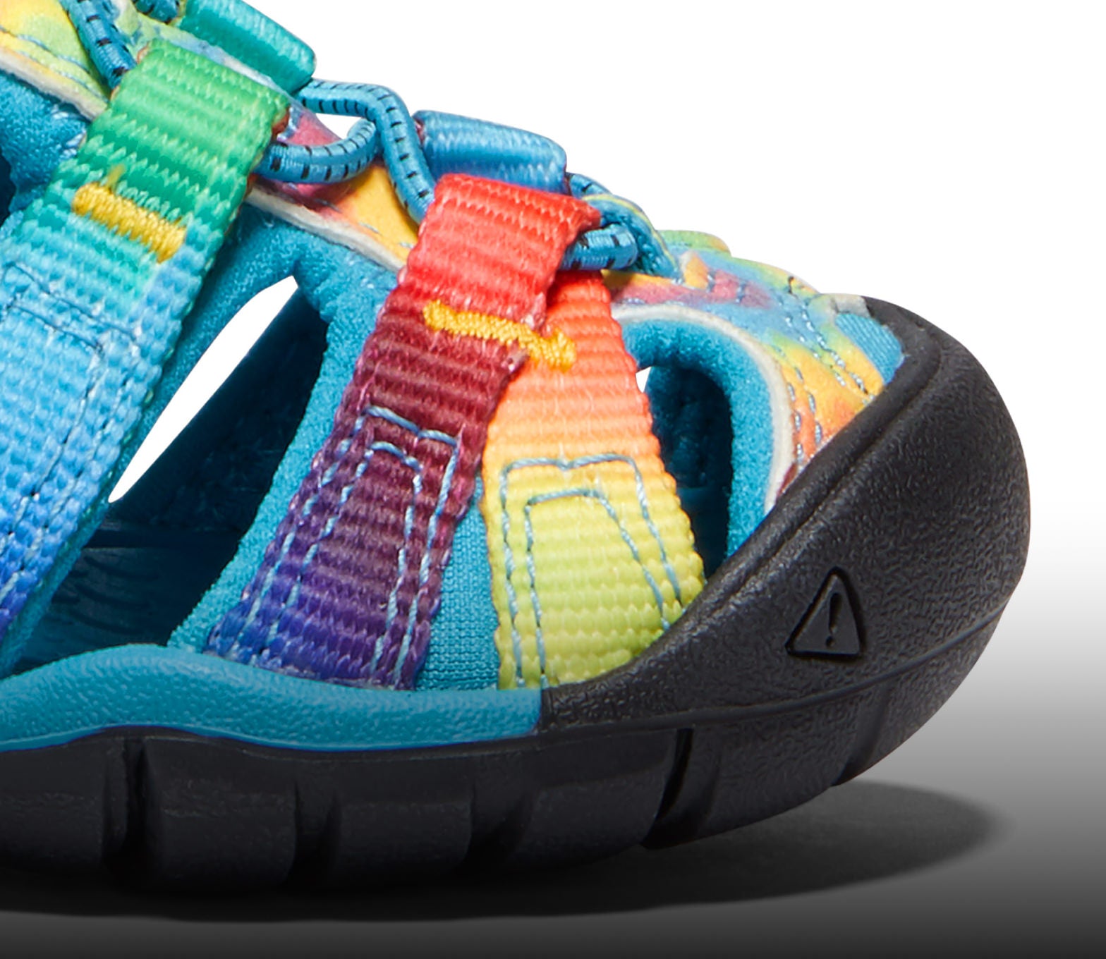 A close-up of the front of a black and tie-dye Seacamp sandal.