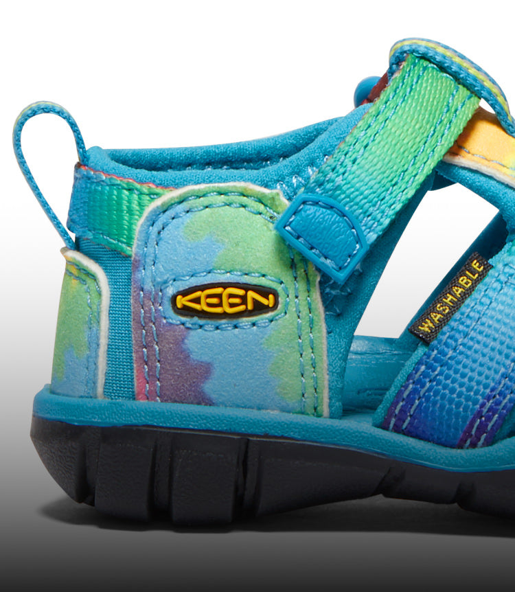 A close-up of a blue and tie-dye Seacamp kids' sandal.