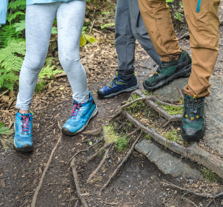 Three people wearing KEEN hiking boots on an outdoor trail.