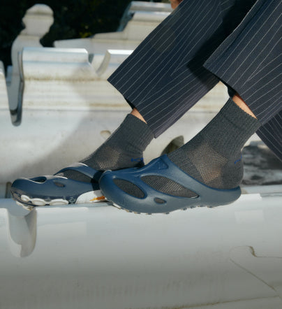 A person wearing a pair of navy blue KEEN Yogui slide sandals.