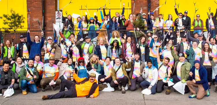 Keen employes posing for a group photo holding up trash collectors and wearing tie-dye