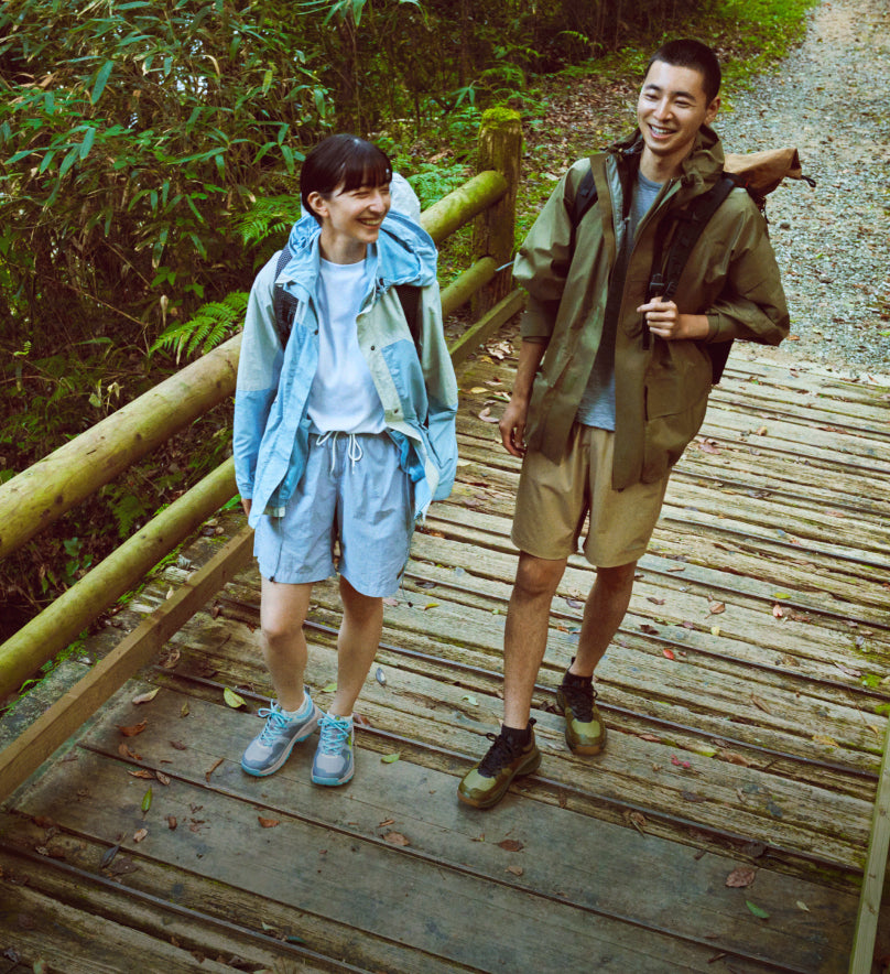 Man and woman walking over a wooden bridge in the forest while wearing Versacore hiking shoes. 
