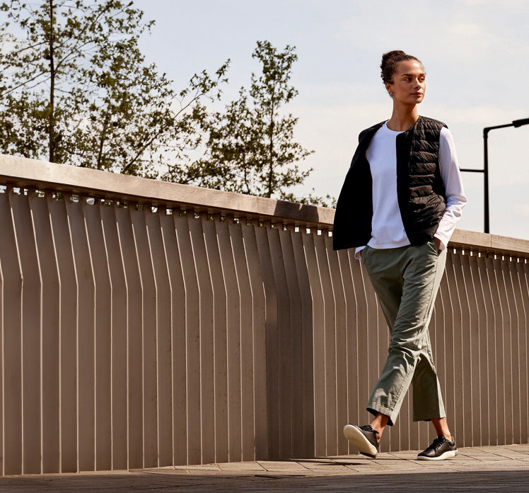 A woman walking outside, wearing a pair of KEEN KNX sneakers.