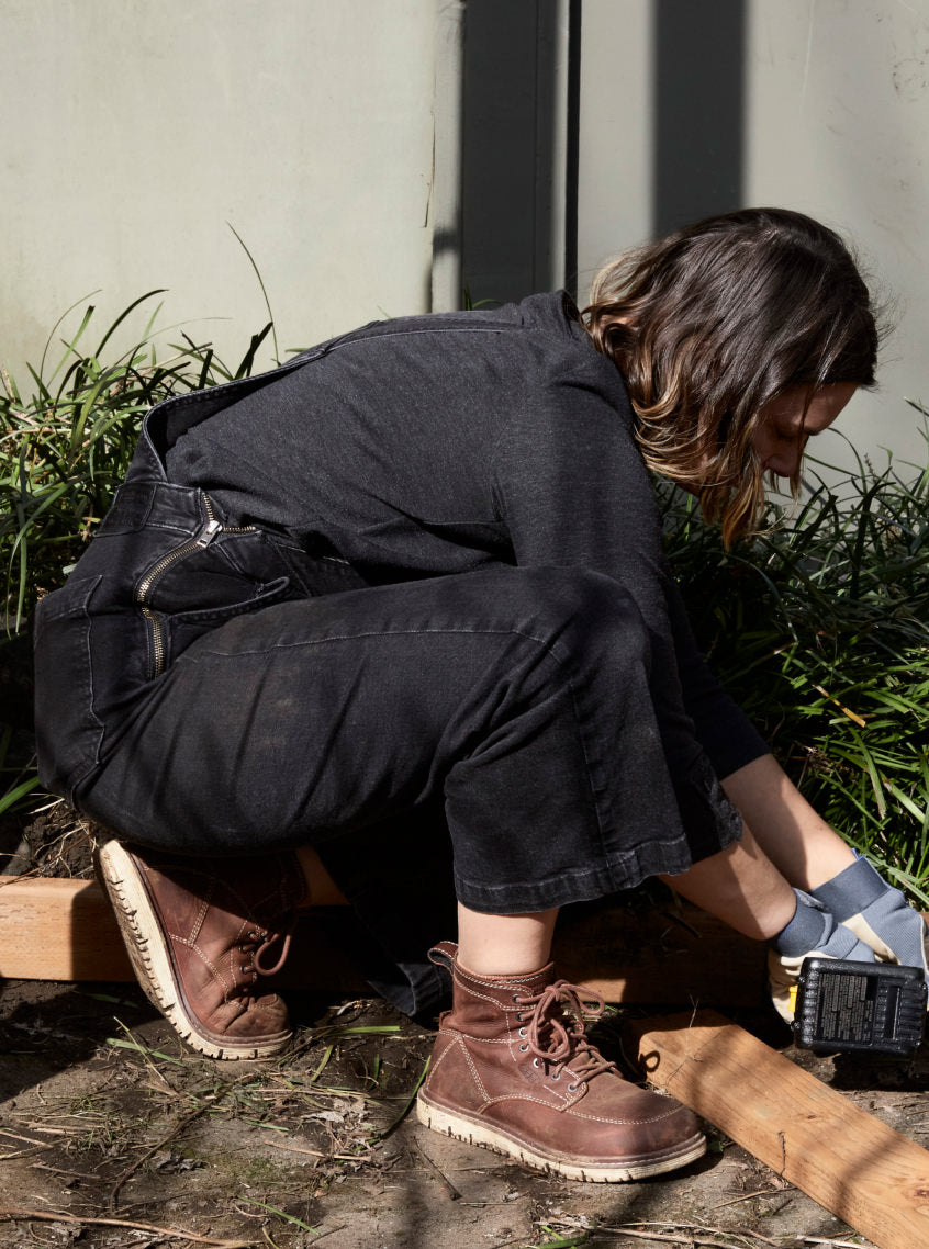 Woman wearing San Jose workboots doing a wood project in yard