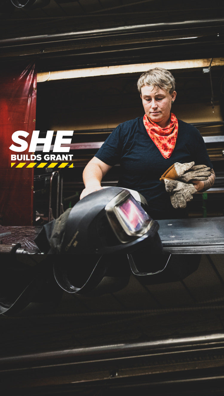 Woman welder holding her gloves in front of machinery 
