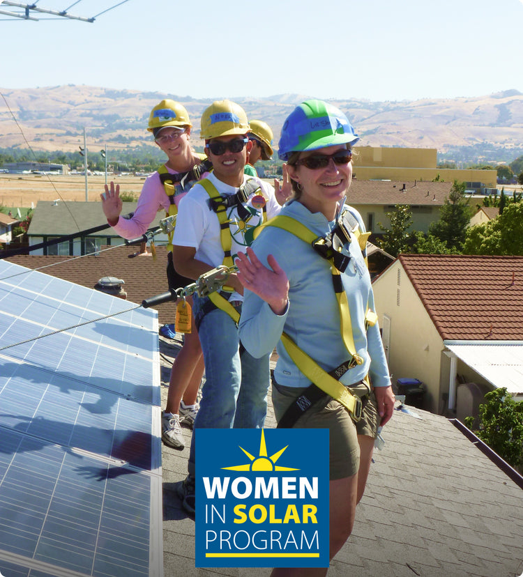 Three women in saftey helmets and harnesses working on solar panels on rooftop 