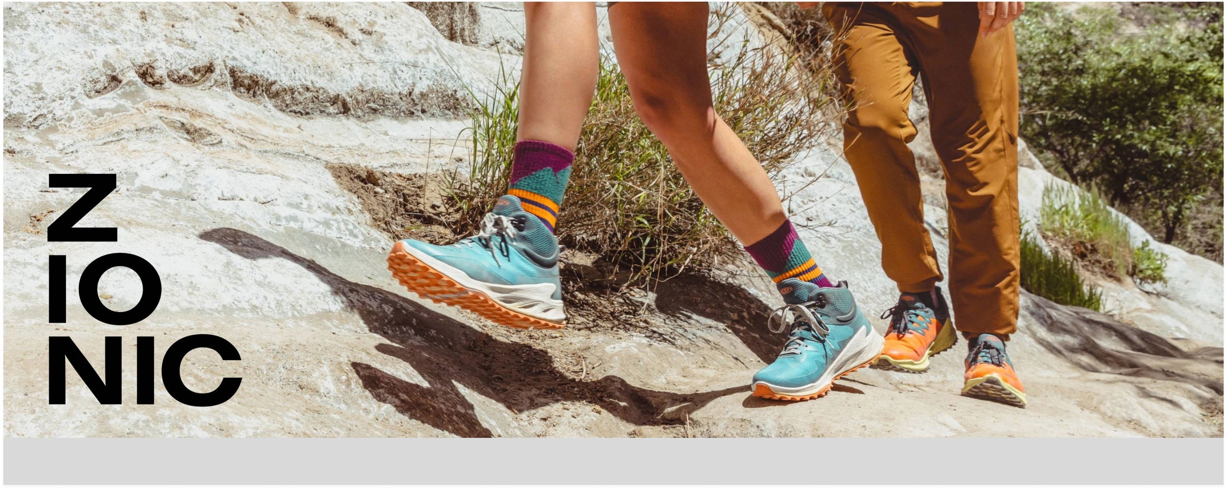 Man and woman wearing blue and orange Zionics hiking up rocky path