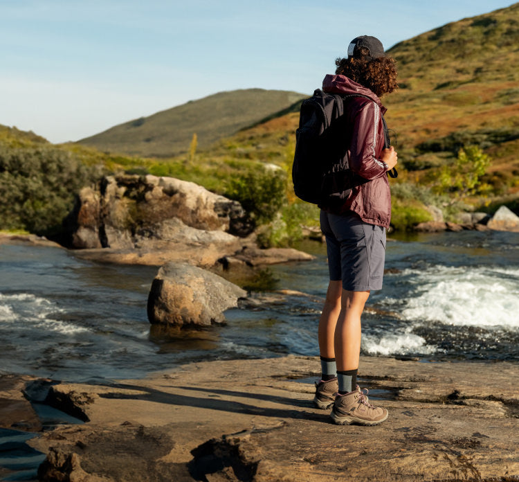 A person standing on a rock next to a river, wearing Targhee IV hiking boots.