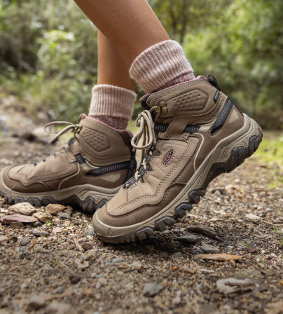A person walking outside, wearing a pair beige KEEN Targhee hiking boots.