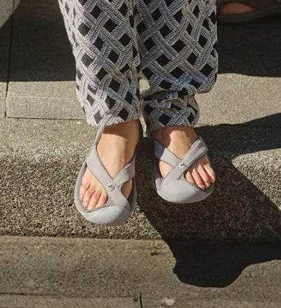 A person wearing light grey KEEN flip-flops with a toe bump.