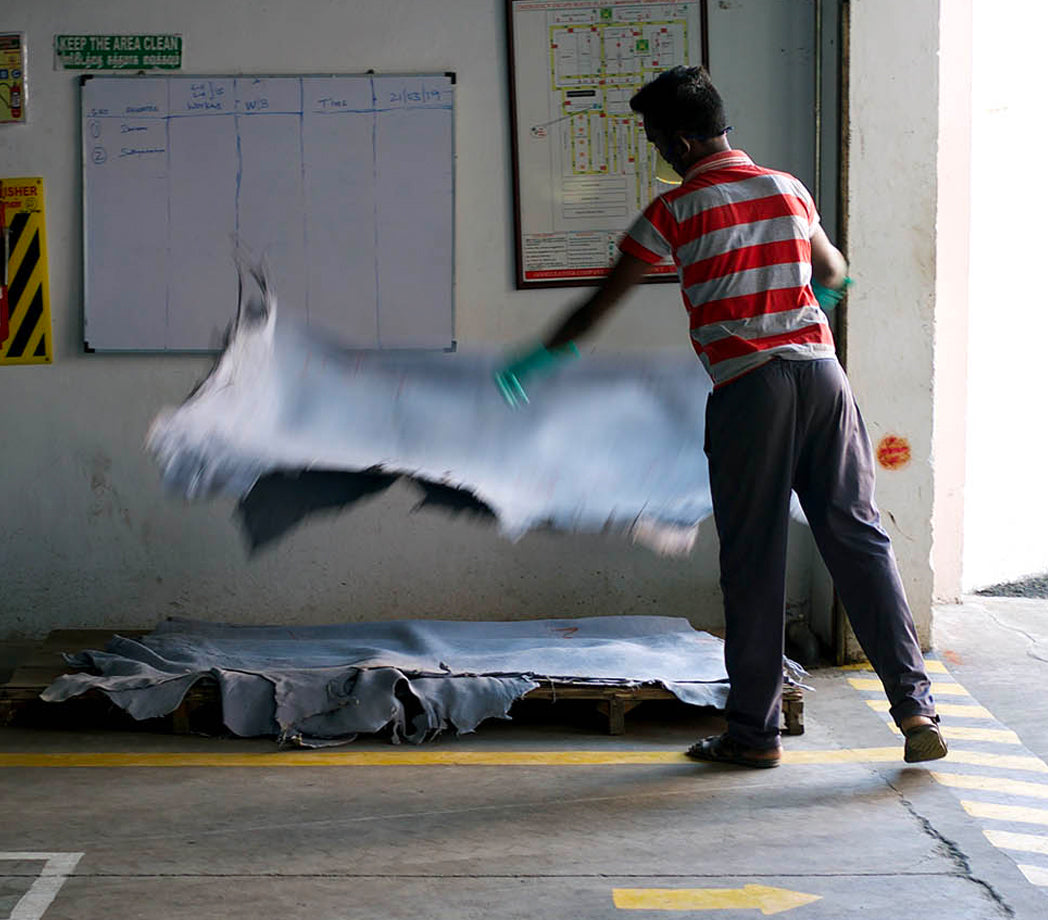 A person throwing a large sheet of fabric onto a wooden platform.