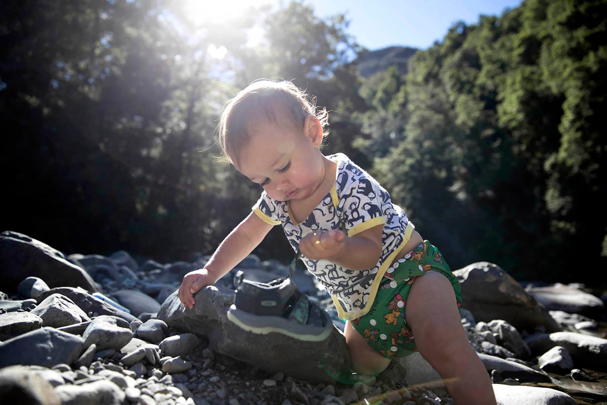 child leaning on rocks in a small stream
