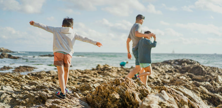 A child with airplane arms at the beach with his family