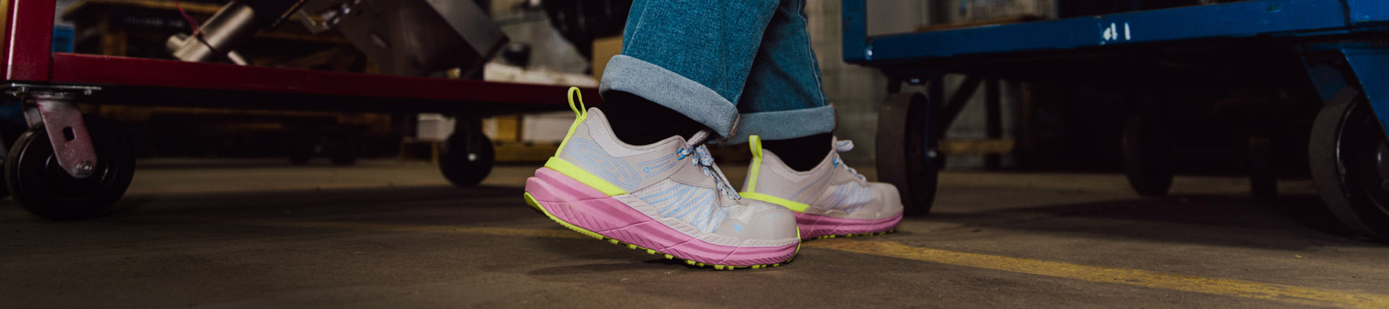 Someone's feet shown wearing KEEN's slip resistant work shoes in pink/cream/yellow.