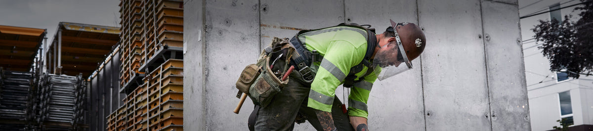 A construction worker in protective gear, operating machinery on an outdoor worksite.