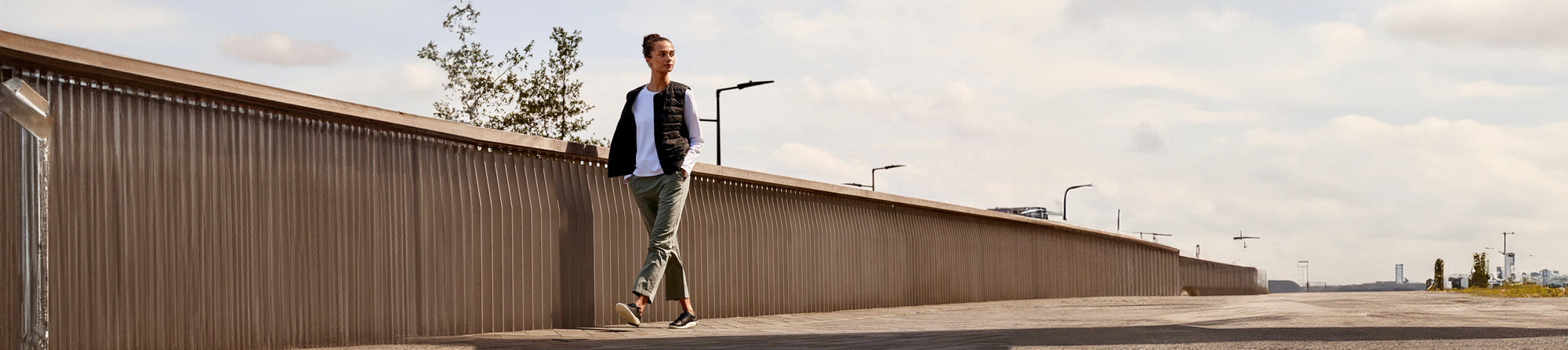 Woman walking along a pier on a sunny day, wearing KEEN footwear