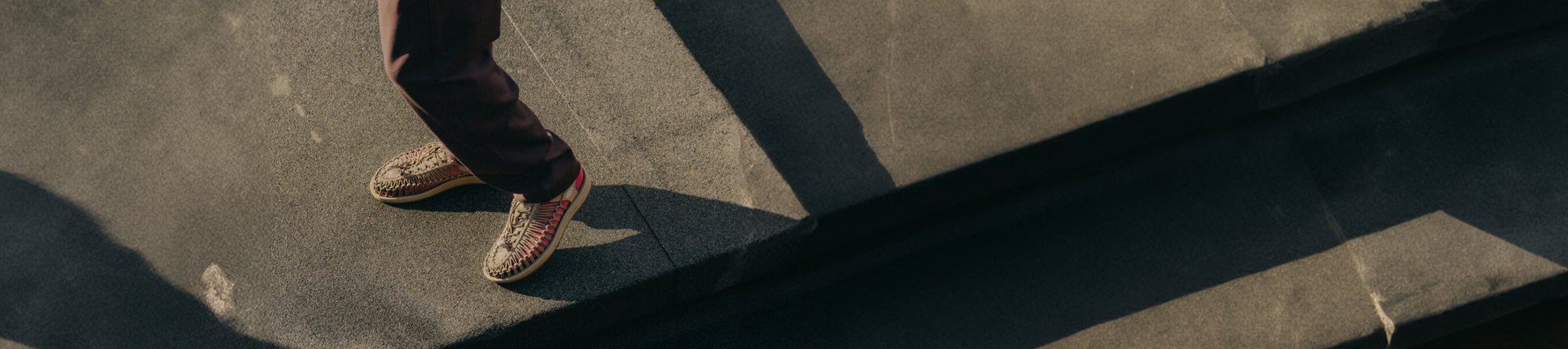 Person wearing KEEN UNEEK sandals on sunny cement steps