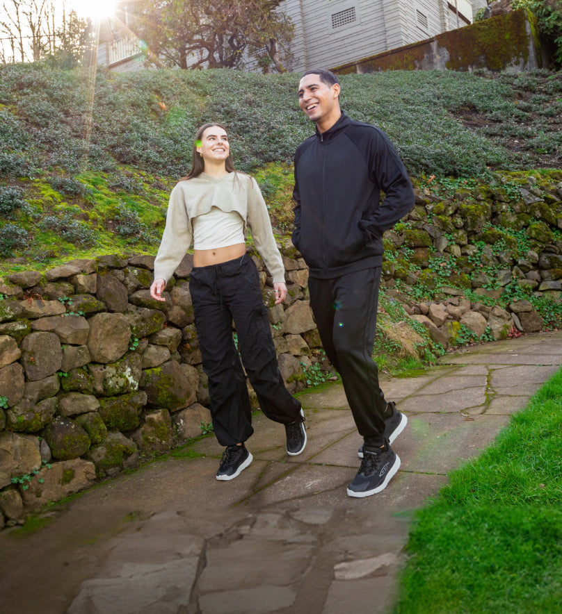Man and woman walking down neighborhood sidewalk and wearing black Wk450 walking shoes. 