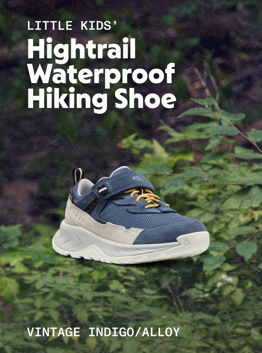 Product shot of Little Kid's Hightrail Waterproof Hiking Shoe in Vintage Indigo and Alloy against forested background. 