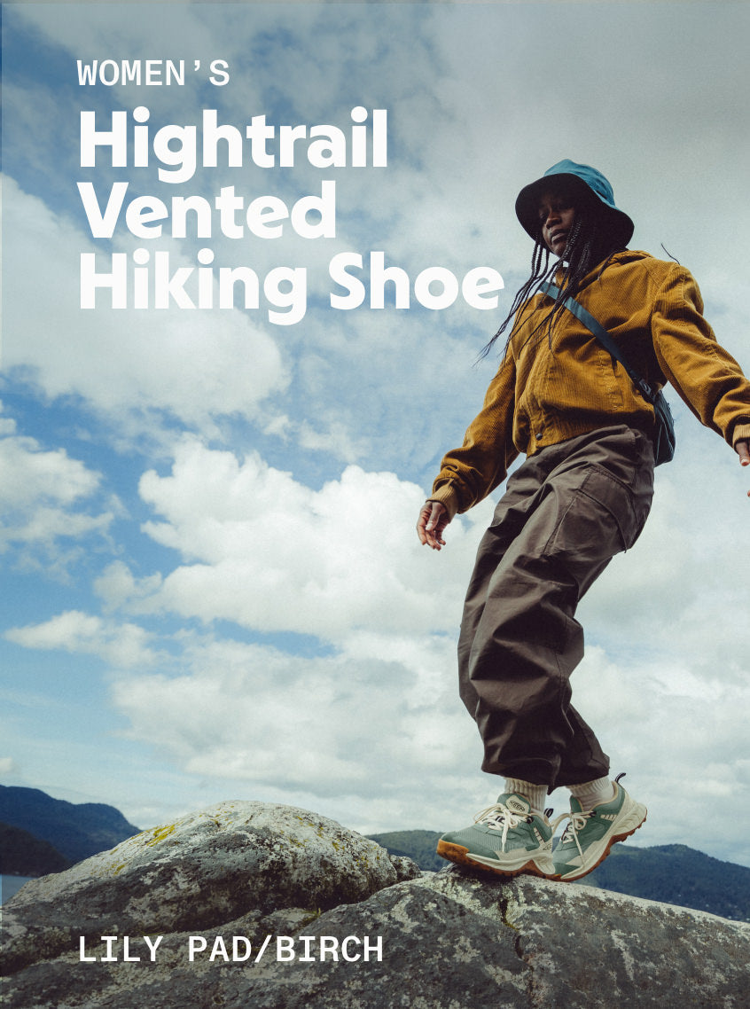 A lady standing on a large rock while wearing Women's Hightrail Vented Hiking Shoe in Lily Pad and Birch.