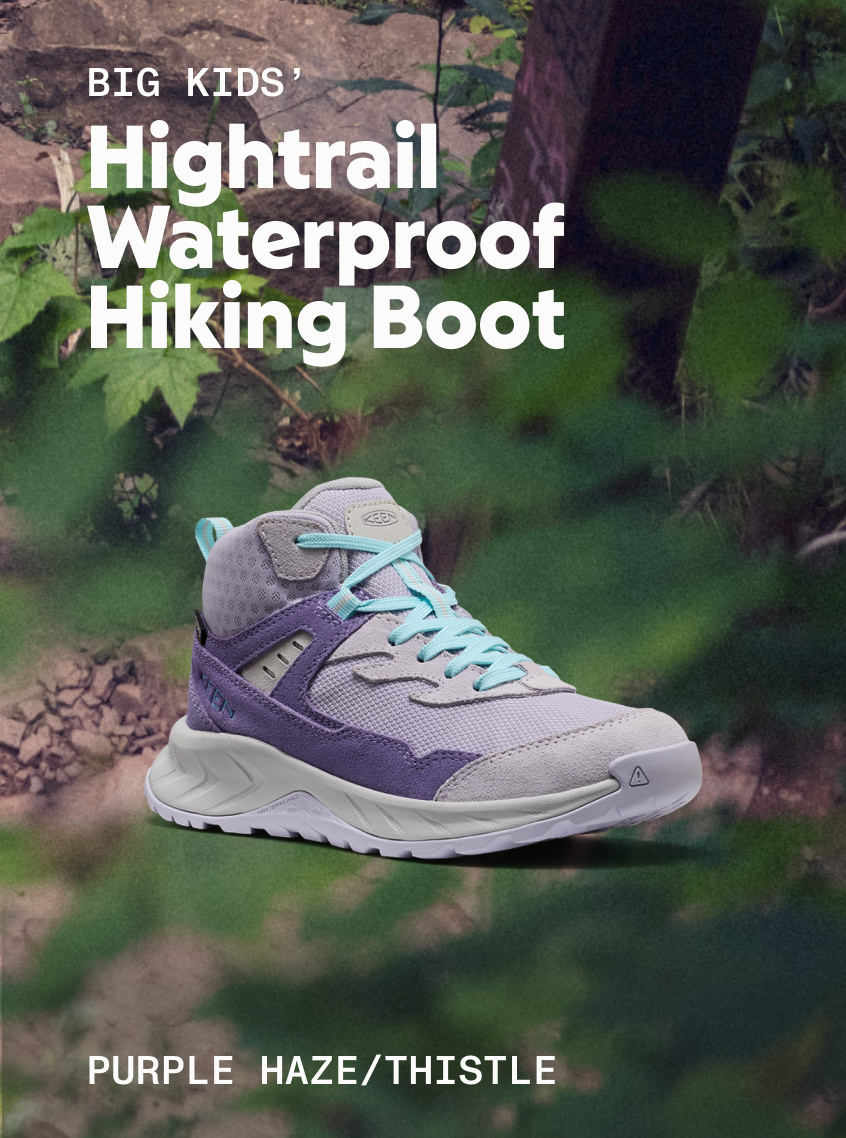 Product shot of Big Kid's Hightrail Waterproof Hiking Boot in Purple Haze and Thistle against forested background. 