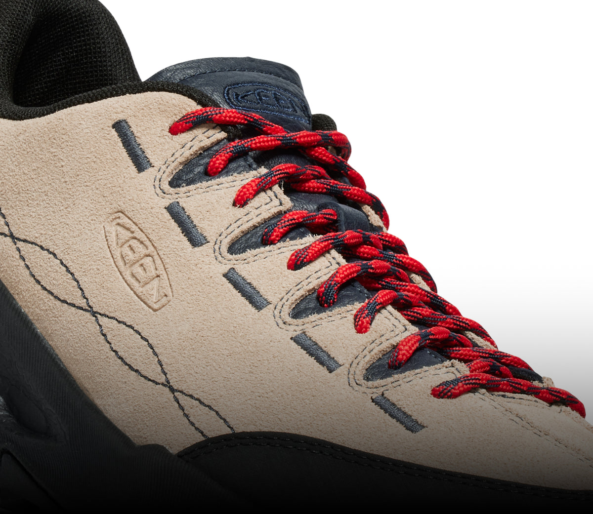 A close-up of a brown and black KEEN sneaker with red shoe laces.
