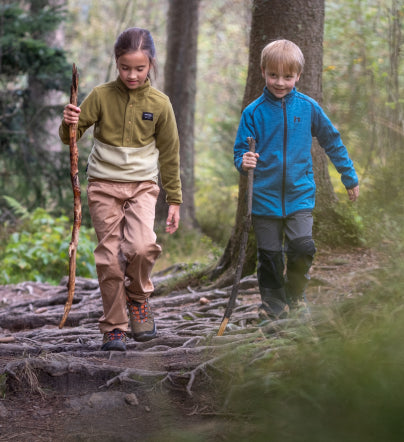 Little boy and girl using walking sticks and hiking on forest trail while wearing  kids' Targhee IV hiking shoes. 