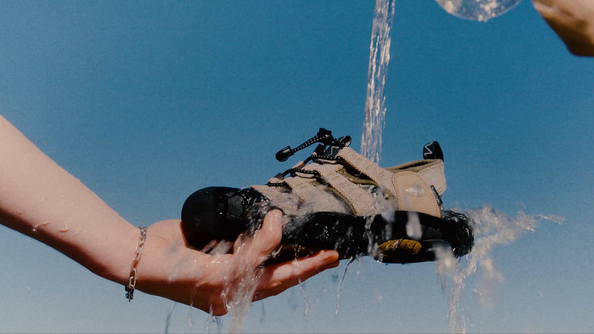 Close-up shot of water being poured onto tan and black KEEN and Gramicci collaboration Newport hiking sandal