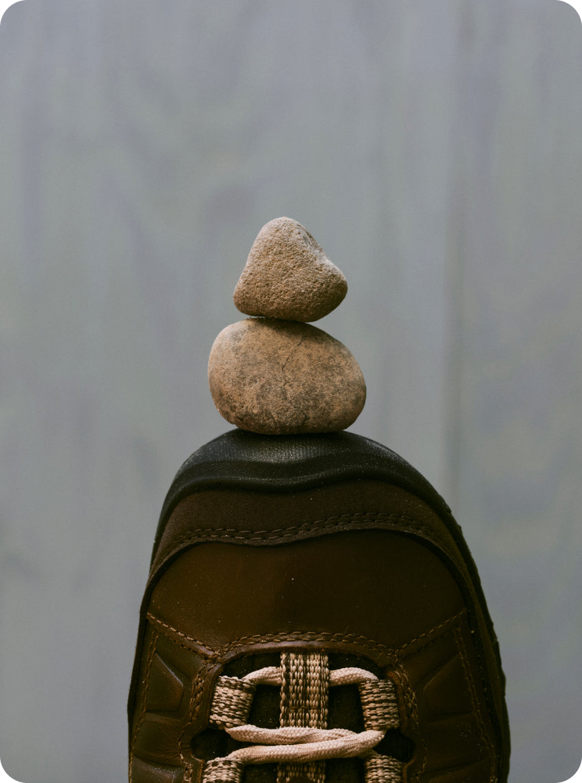 Toe of Hikerkind and Keen collaboration leather hiking boot balancing two rocks on the toe
