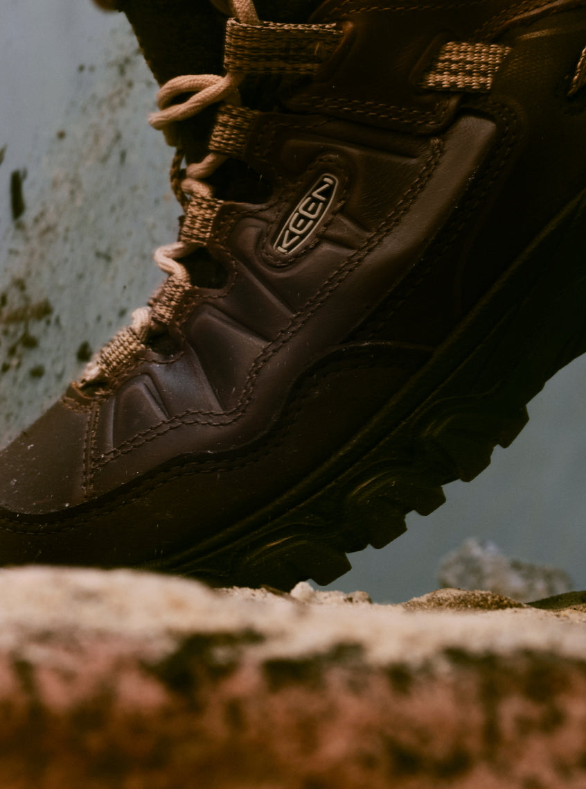 Product shot of Hikerkind and Keen collaboration leather hiking boot on rocky surface.