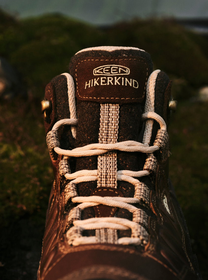 Product shot of Hikerkind and Keen collaboration leather hiking boot on rocky surface.