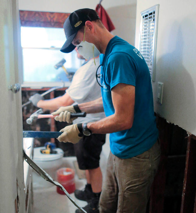 A person wearing a white dust mask, doing manual work inside a house.