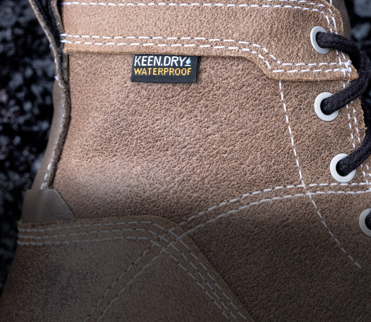 A close-up of a brown KEEN work boot featuring KEEN.DRY waterproof material.