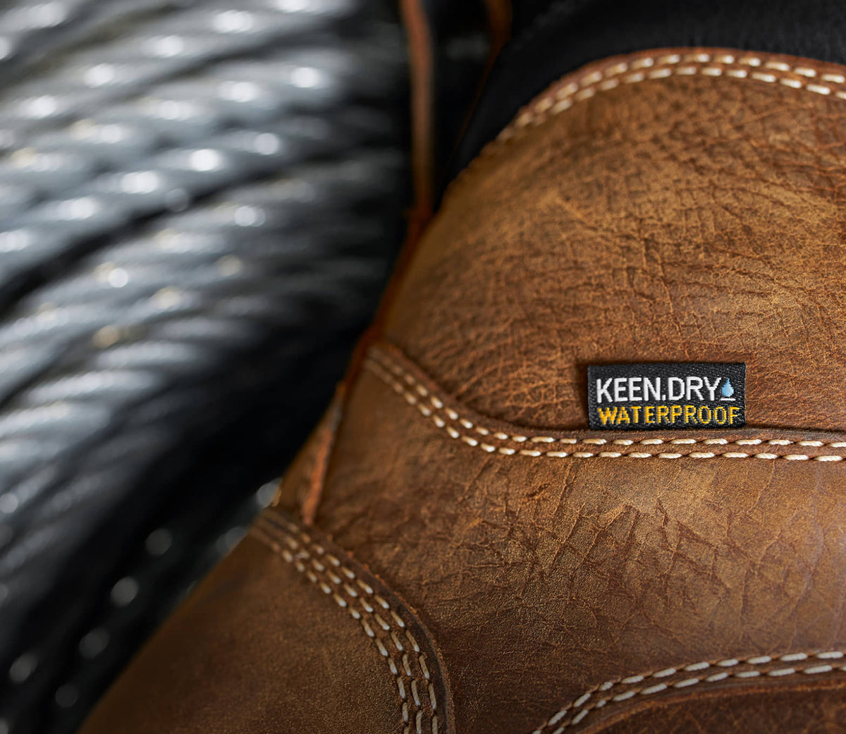 A close-up of a brown and black KEEN work boot featuring KEEN.DRY waterproof material.