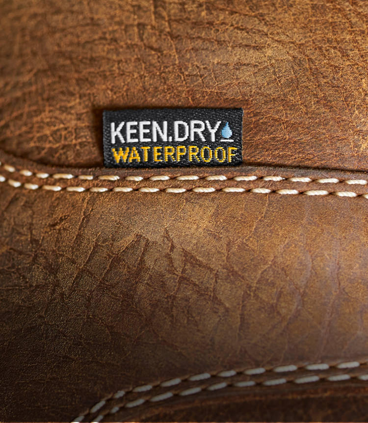 A close-up of a brown KEEN work boot featuring KEEN.DRY waterproof material.