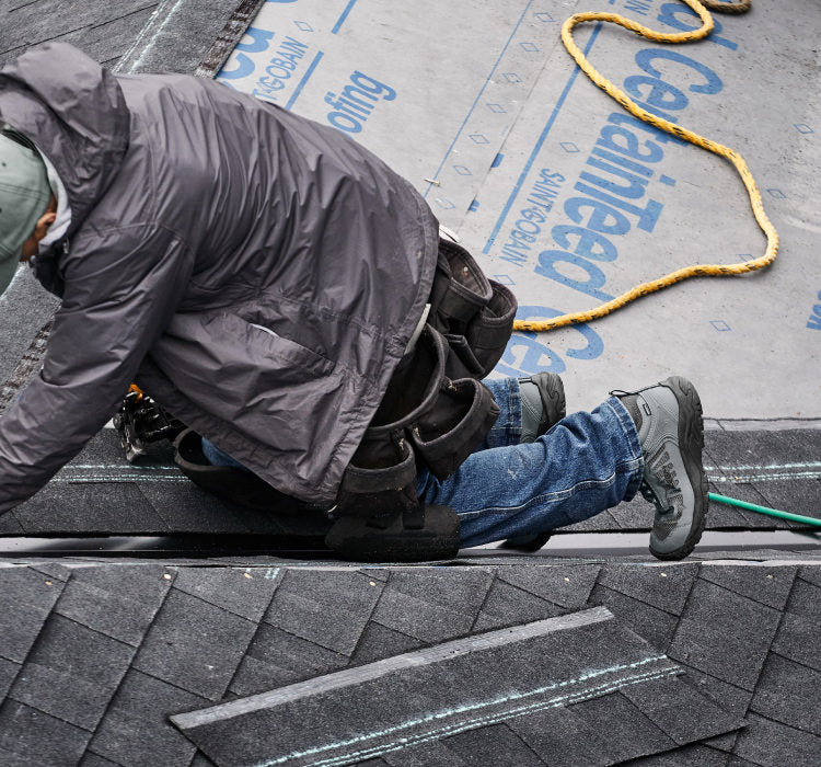 A worker climbing a ladder, wearing a pair of grey KEEN work boots.