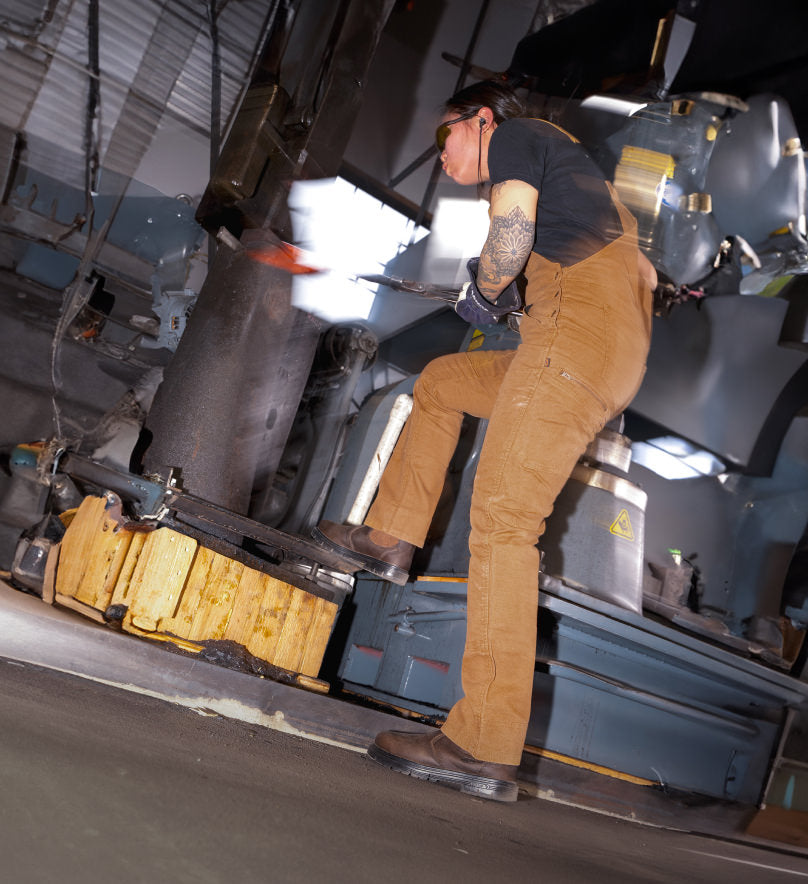 Woman in brown overalls working alongside a large metal machine wearing brown leather San Jose pull-on workboots