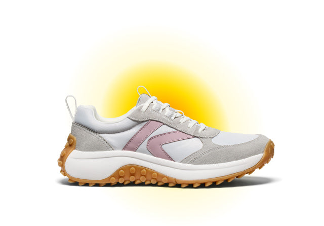 Product shot of women's white, grey and pink casual shoe against white and yellow gradient background