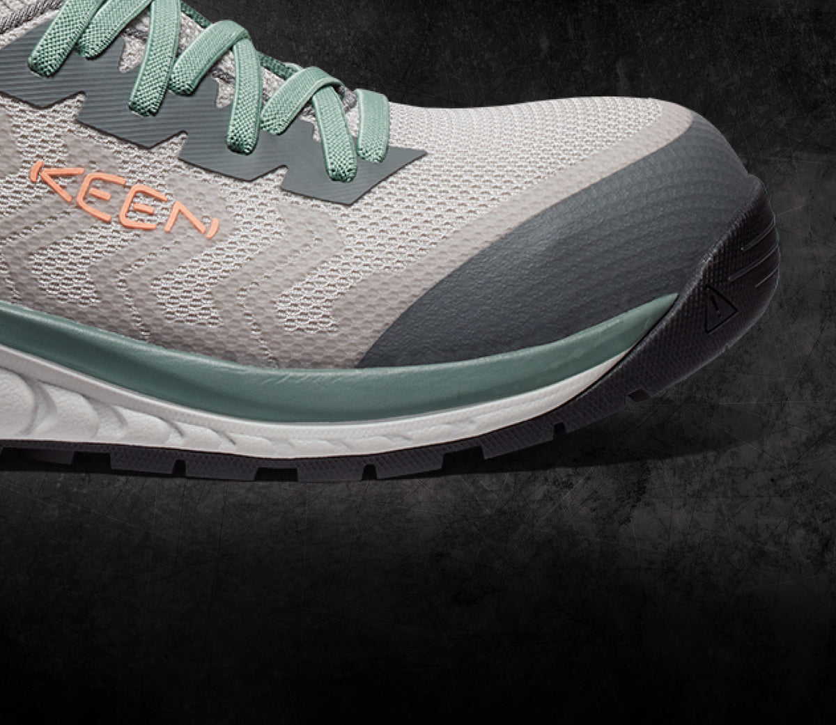 A close-up of a grey and mint green KEEN work sneaker.