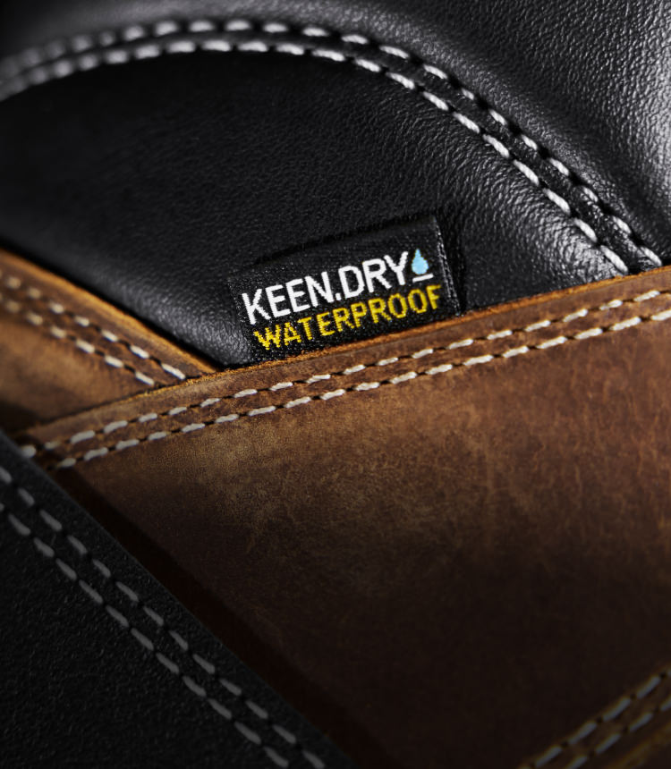 A close-up of a brown and black KEEN work boot featuring KEEN.DRY waterproof material.