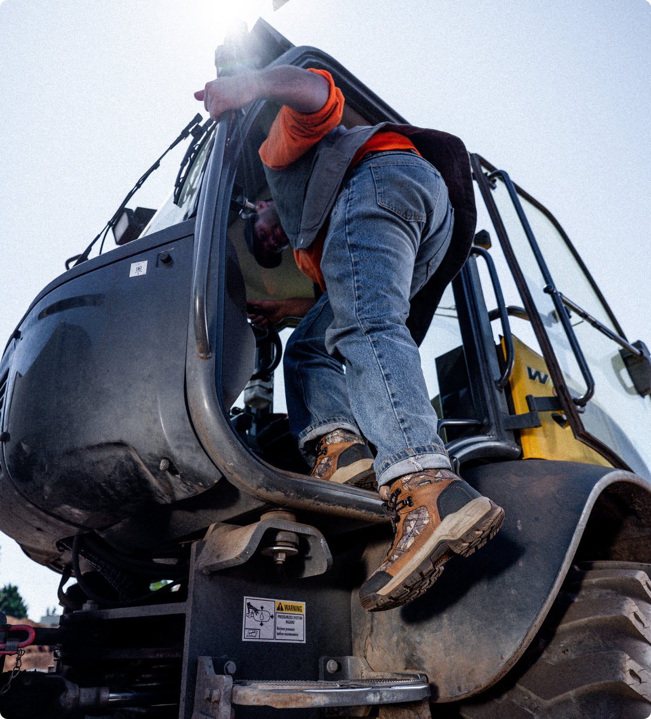 Man wearing Keen utility work boots while climbing into tractor 