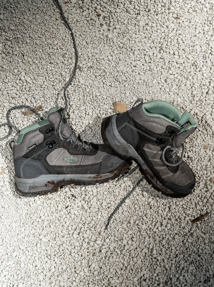 Product shot of Womens gray and teal Skokie work boots on tiny gray gravel ground