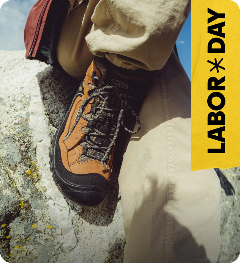 Knee down shot of man in brown leather KEEN hiking boots sitting on rock. Embedded text reads 