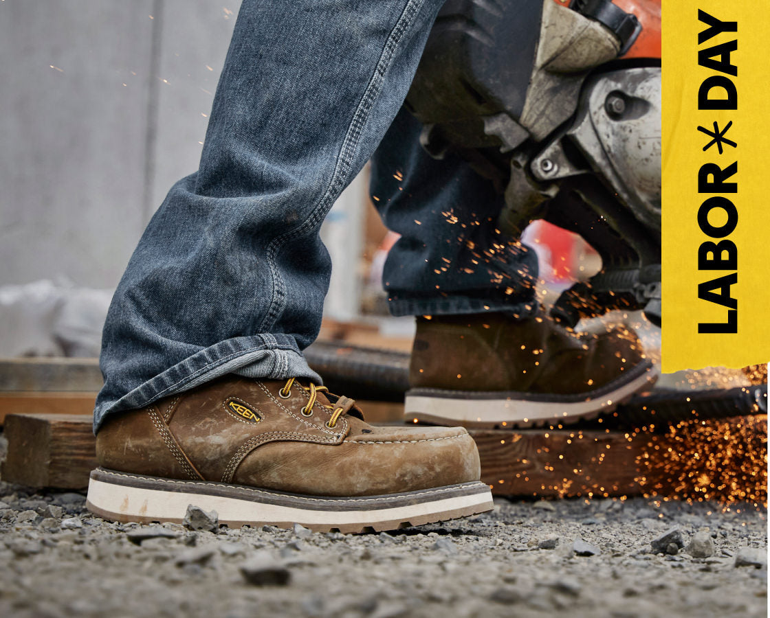 Knee-down shot of man in KEEN leather work boots using a metal grinder. Embedded text reads "Labor Day" in yellow. 