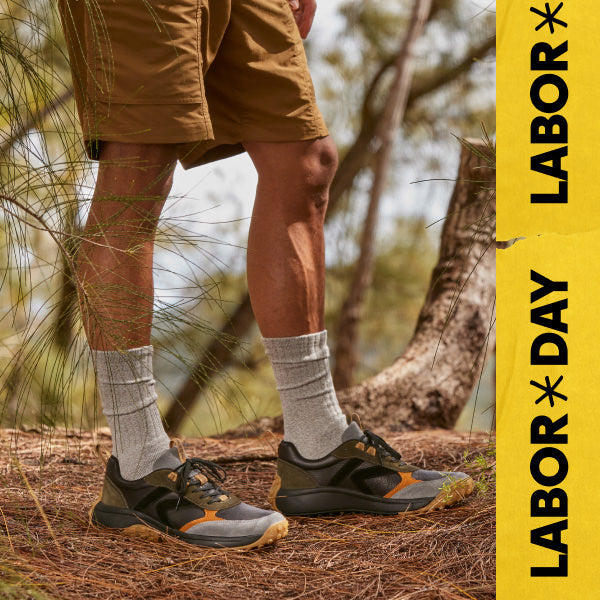 Waist down shot of man in Keen KS86 casual sneakers and crew socks standing in piney forest. Embedded text reads "Labor Day" in yellow. 